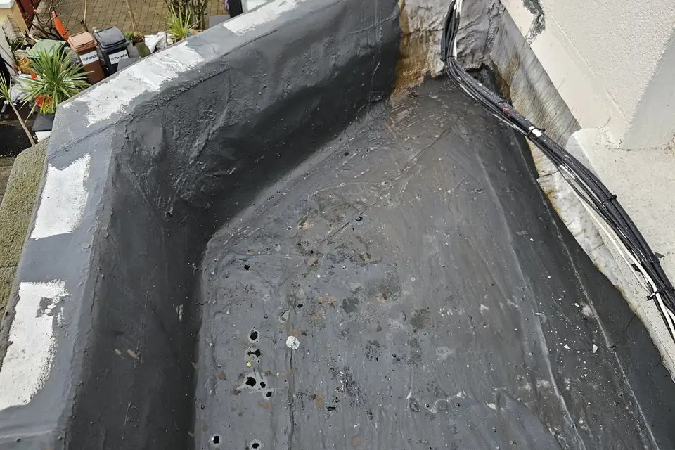 Parapet gutter lined behind a wall