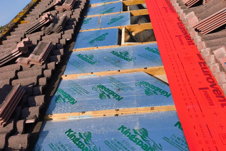 Rigid insulation boards fitted between rafters next to new breathable membrane