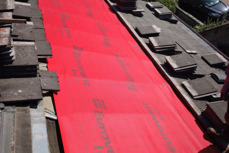 Breathable membrane fitted on a roof slope with tiles stacked ready to re-lay