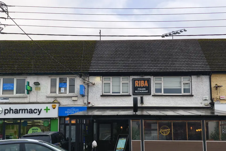 Tiled roof above a row of shops with a pharmacy on the ground floor