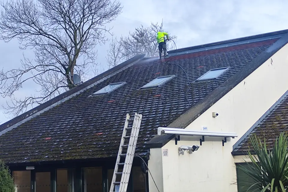 Roofer on a pitched roof with a ladder at the gable