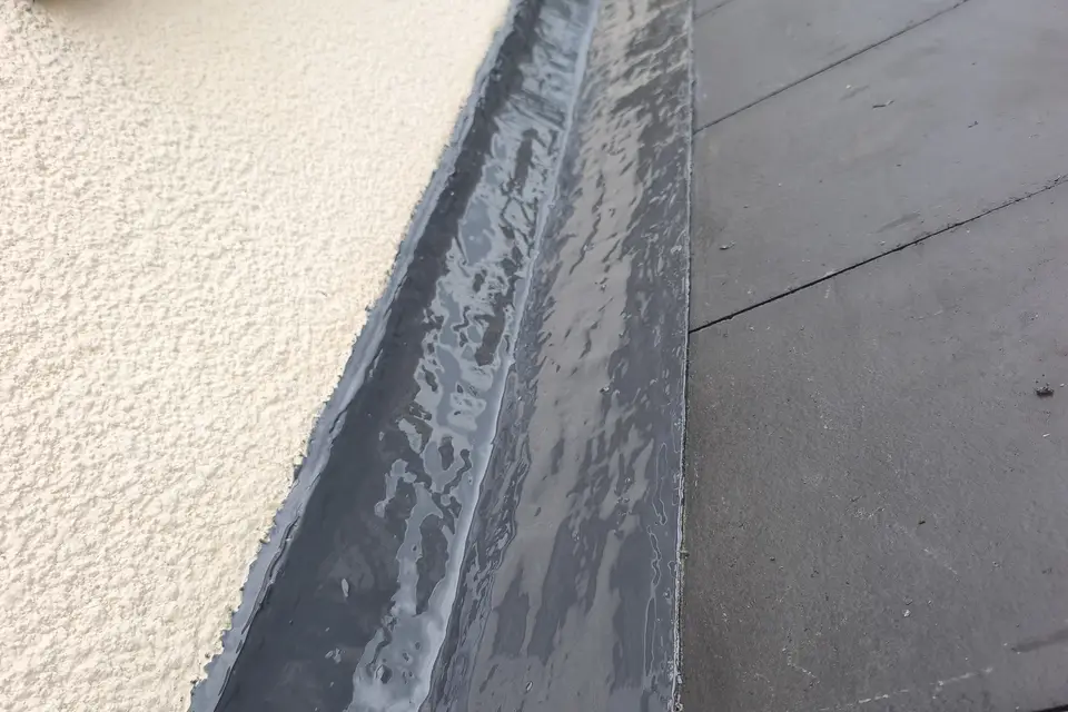 Flat roof upstand and flashing against a rendered wall